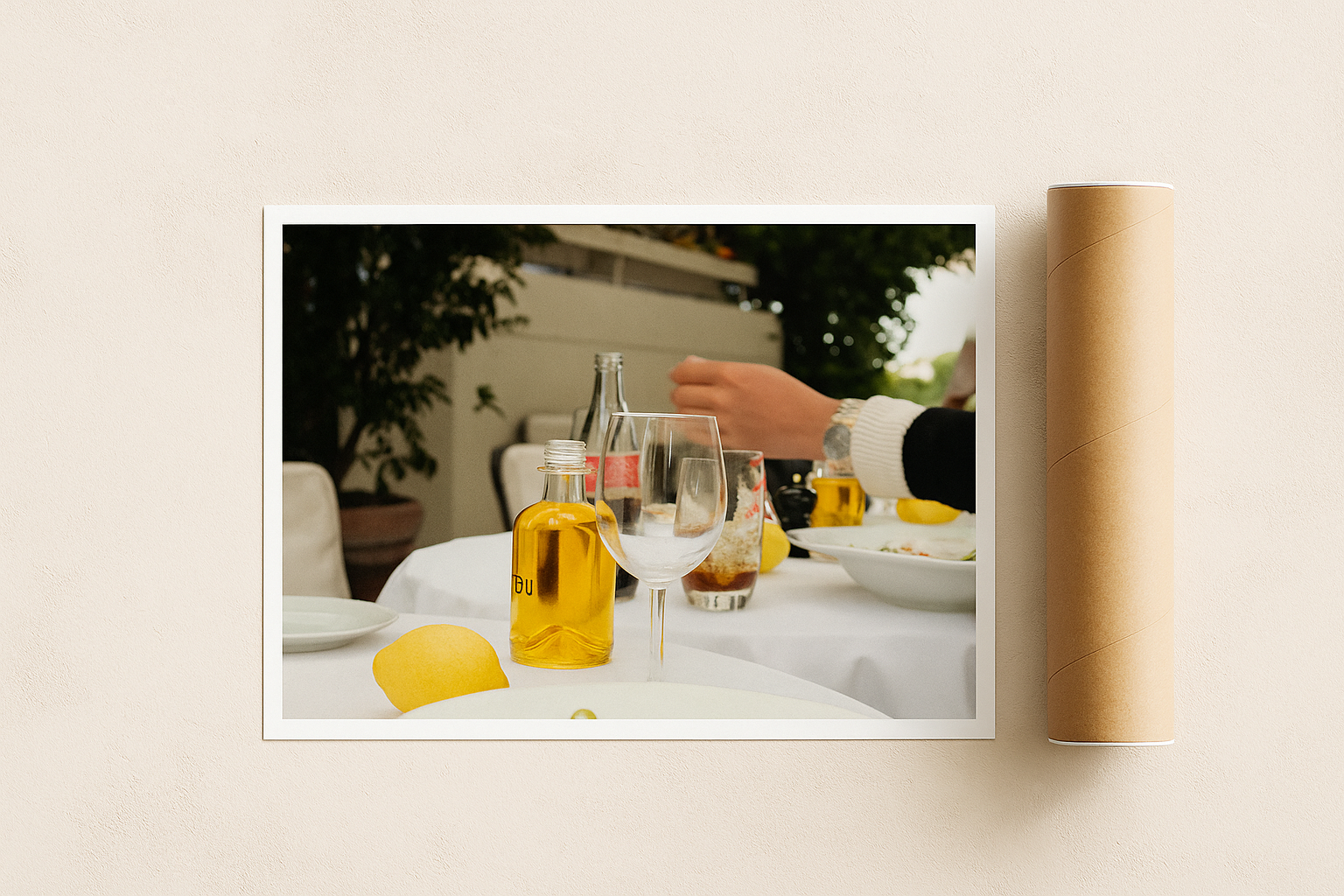 Framed photograph of a person at an outdoor dining table with bottles and glasses.